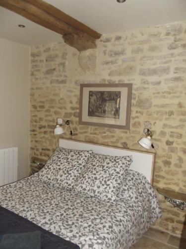 a bedroom with a bed and a stone wall at Chambre d´hote En Famille in Bayeux