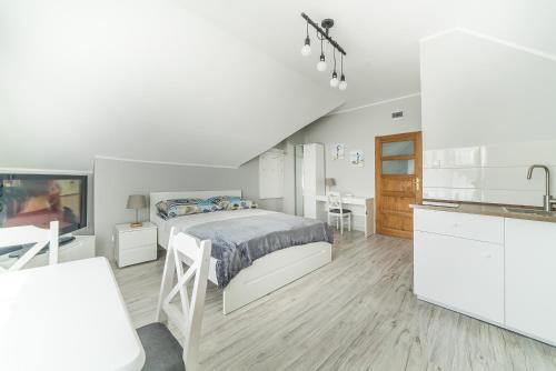 a white bedroom with a bed and a kitchen at Niebieska Willa in Jastarnia