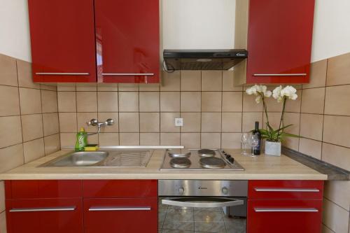 uma cozinha com armários vermelhos e um lavatório em Apartments Ive - with sea view em Tisno