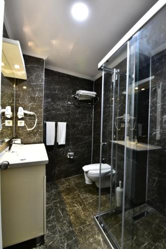 a bathroom with a toilet and a glass shower at Ayaz Aqua Beach Hotel in Gümbet