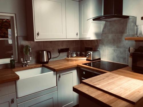 a kitchen with white cabinets and a sink and a stove at A quaint Wymondham cottage in Norwich