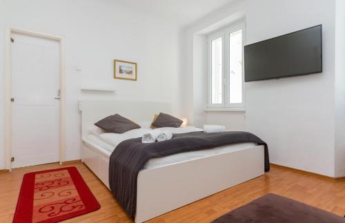 ein weißes Schlafzimmer mit einem Bett und einem Flachbild-TV in der Unterkunft Apartment Petka in Piran