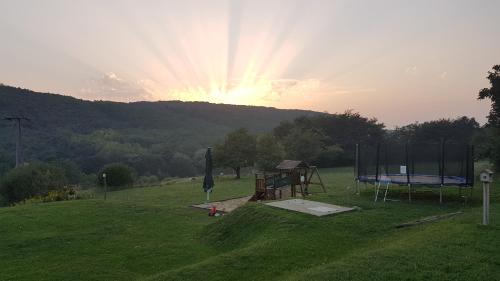 a playground in a field with the sun in the background at Pálos Resort in Zalacsány