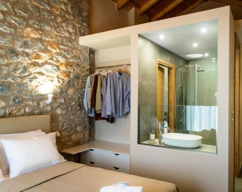 a bedroom with a bed and a bathroom with a sink at Petras Gi - Stone Houses in Stoupa