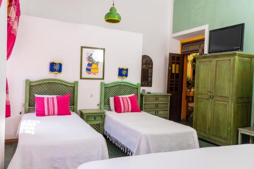 deux lits dans une chambre rose et verte dans l'établissement Casa Vilasanta, à Guadalajara