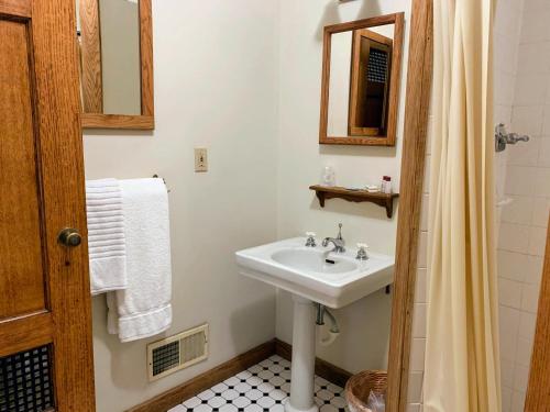 W białej łazience znajduje się umywalka i lustro. w obiekcie Gordon Beach Inn w mieście Union Pier