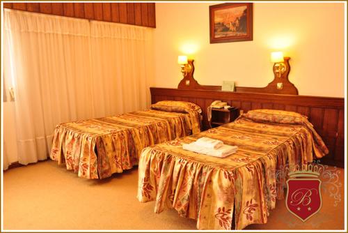 two beds in a hotel room with two tables at Hotel Berlin in Gualeguaychú
