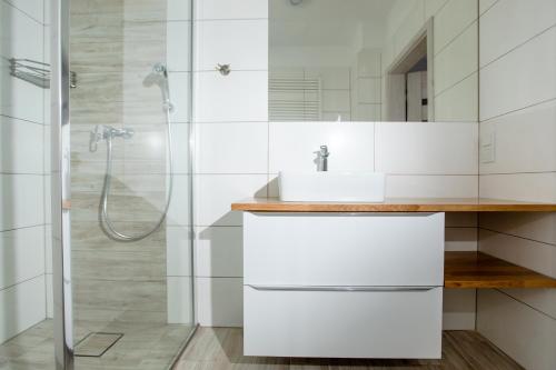 a white bathroom with a sink and a shower at Apartament NA WYDMIE Gardenia Dziwnów z widokiem na morze EPapartamenty in Dziwnów
