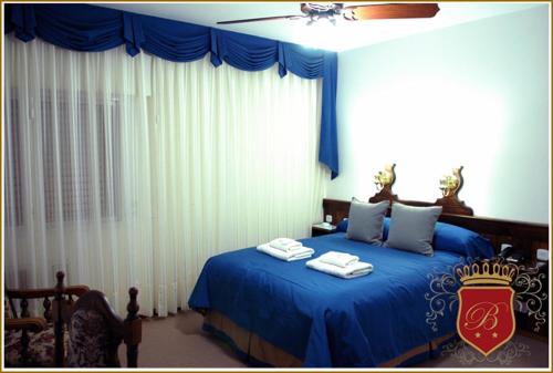 a bedroom with a blue bed with towels on it at Hotel Berlin in Gualeguaychú