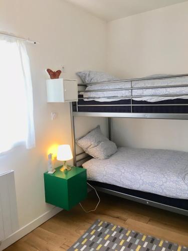 a room with two bunk beds and a lamp at La maison des amis in Nuits