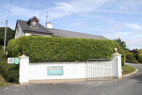 a white house with a hedge on the side of a street at Marguerite's B&B in Skibbereen