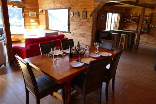 a dining room with a wooden table with wine glasses at LA CABAÑA FISHING LODGE in Puerto Ramírez