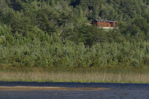 a house on the side of a hill near the water at LA CABAÑA FISHING LODGE in Puerto Ramírez