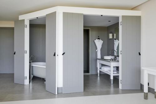 a bathroom with white walls and a tub and a sink at Hôtel Plage Palace & Spa in Palavas-les-Flots