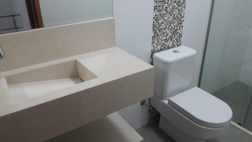 uma casa de banho branca com um WC e um lavatório em Condomínio frente ao mar em Boiçucanga