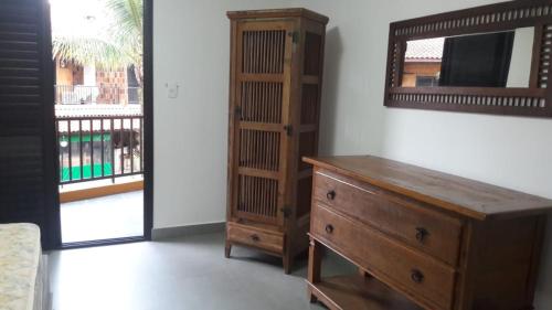 Cette chambre comprend une commode en bois et un miroir. dans l'établissement Condomínio frente ao mar, à Boicucanga