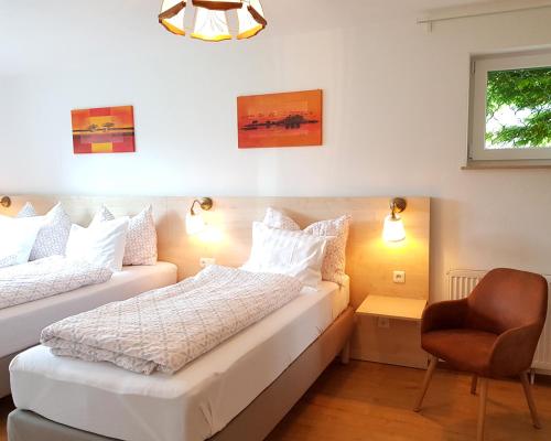 a bedroom with two beds and a chair in it at Aparthotel Pan Haus in Bad Ischl