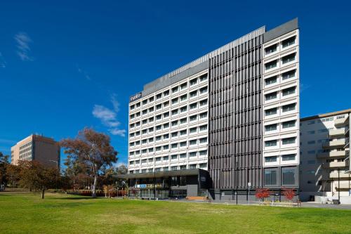 a large office building with a park in front of it at Mantra MacArthur Hotel in Canberra