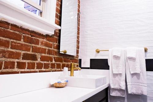 a bathroom with a sink and a brick wall at H by H Hospitality in Los Angeles