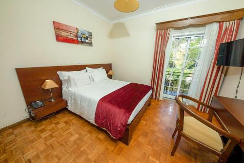 1 dormitorio con cama, escritorio y ventana en Hotel Beira Dão, en São Gemil