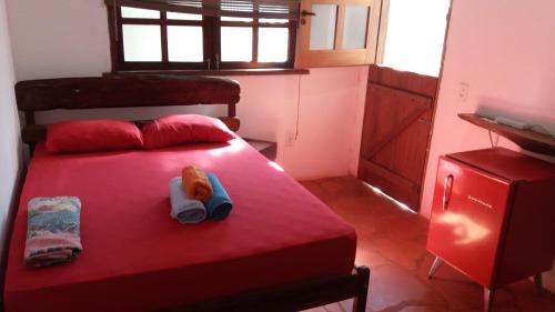 Una cama roja con un animal de peluche sentado en ella. en Sweet Suíte São Jorge, en São Jorge