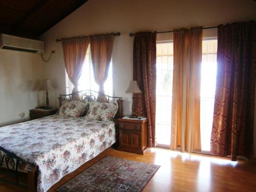 ein Schlafzimmer mit einem Bett und zwei großen Fenstern in der Unterkunft Prime Ocean View Vacation Villa in Plaisance