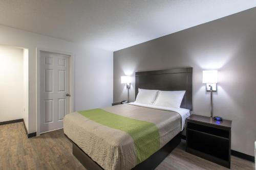a bedroom with a large bed with a green blanket at Studio 6-Greenville, SC - I-85 Near Downtown in Greenville
