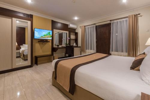 a hotel room with a large bed and a television at Vila Ombak in Gili Trawangan
