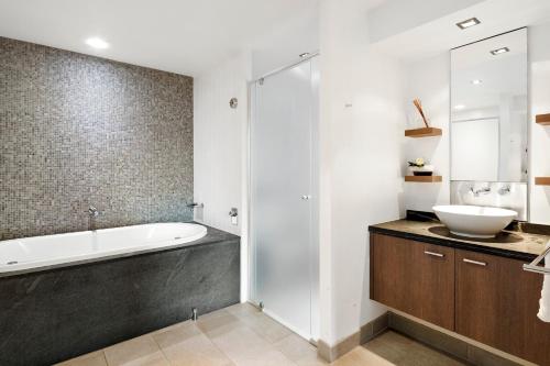 a bathroom with a bath tub and a sink at Temple 304 Modern Spacious Palm Cove Resort in Palm Cove