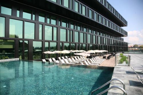 a swimming pool in front of a building with chairs and umbrellas at Axis Viana Business & SPA Hotel in Viana do Castelo