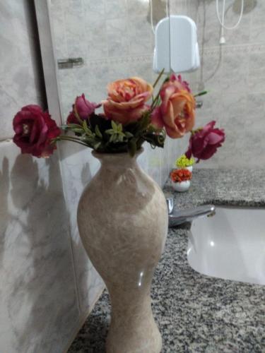 a vase filled with flowers on a counter in a bathroom at Pousada Santa Lolla in São Carlos