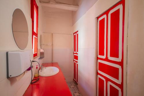 baño con puertas rojas, lavabo y espejo en Botanico Hostel, en Bogotá