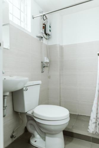 a white bathroom with a toilet and a sink at San Agustin Residences in Manila