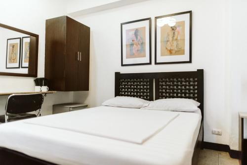 a bedroom with a white bed and some pictures on the wall at San Agustin Residences in Manila