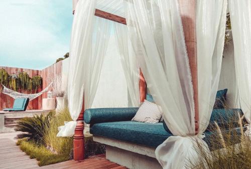 a bench on a deck with white curtains at Maldives Beach Resort in Chao Lao Beach