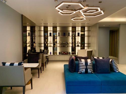 a lobby with a blue couch and a table and chairs at The Nature Phuket - SHA Extra Plus in Patong Beach