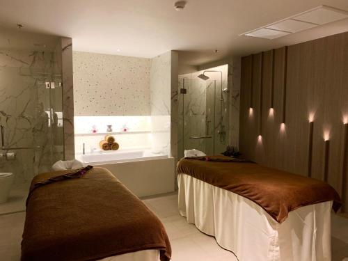 a bathroom with two beds and a shower and a tub at The Nature Phuket - SHA Extra Plus in Patong Beach