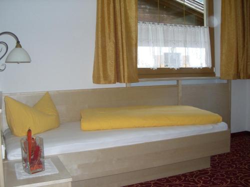 a bed with yellow pillows and a window at Landhaus Hofer in Neustift im Stubaital