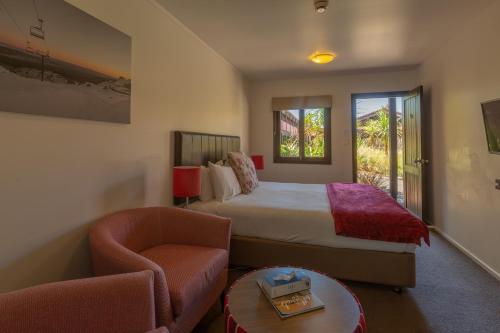 um quarto de hotel com uma cama e uma cadeira em The Park Hotel Ruapehu em National Park