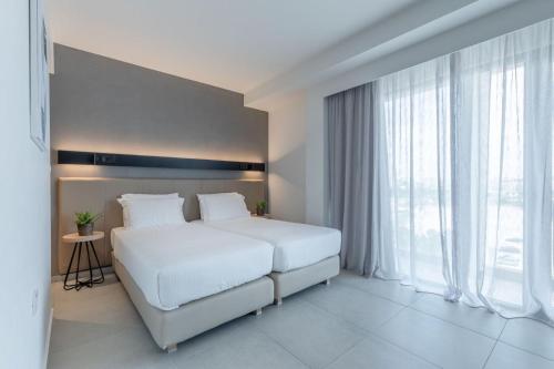 a bedroom with a white bed and a large window at Hotel Avra by Smile hotels - Free Airport Shuttle in Rafina