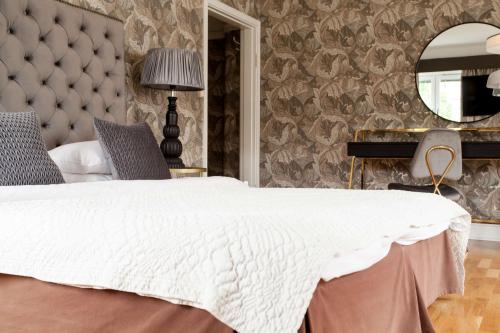 a bedroom with a large white bed and a mirror at Centric Hotel in Norrköping