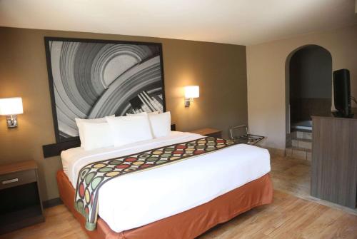 a hotel room with a large bed with a painting on the wall at Super 8 by Wyndham Portsmouth in Portsmouth
