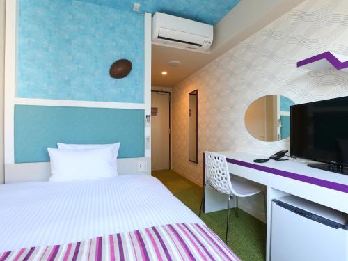 um quarto com uma cama e uma secretária com uma televisão em Hotel Wing International Select Higashi Osaka em Osaka