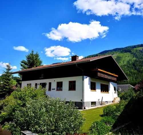 a white house with a black roof on a hill at Haus Edlinger in Hinterstoder