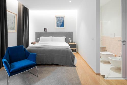 a bedroom with a bed and a blue chair at The Radical Hotel Roma in Rome