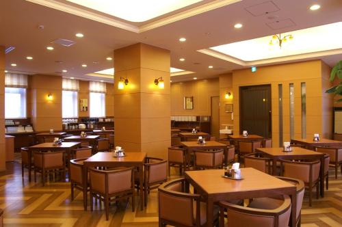 an empty restaurant with wooden tables and chairs at Route Inn Grantia Hakodate Goryokaku in Hakodate