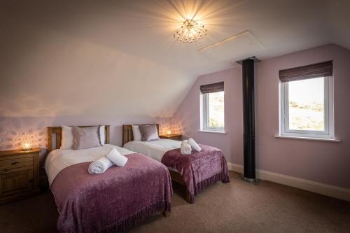 two beds in a room with purple walls and windows at Karinya in Drynoch