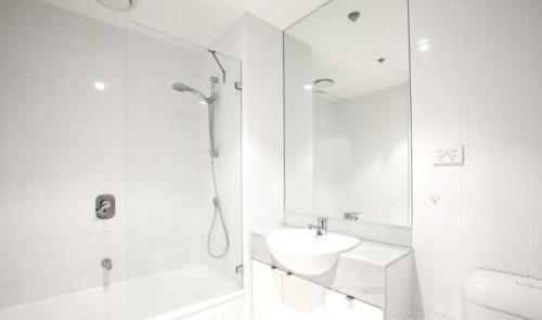 a white bathroom with a shower and a sink at ReadySet Apartments at City Tower in Melbourne