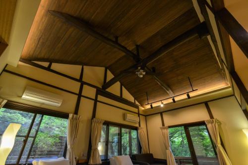 a living room with a wooden ceiling and windows at Villa Hamorebi in Miyajima