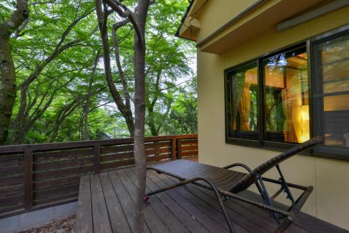a bench sitting on a deck next to a tree at Villa Hamorebi in Miyajima
